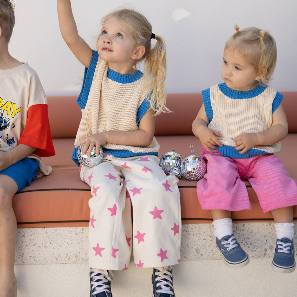 Kindjes op een bankje met roze broek aan 